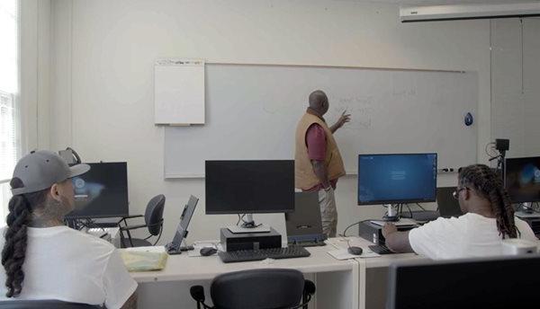 电脑前的学生在白板前听老师讲课